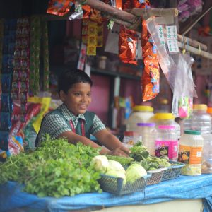 A child in India helping at his family’s vegetable stall